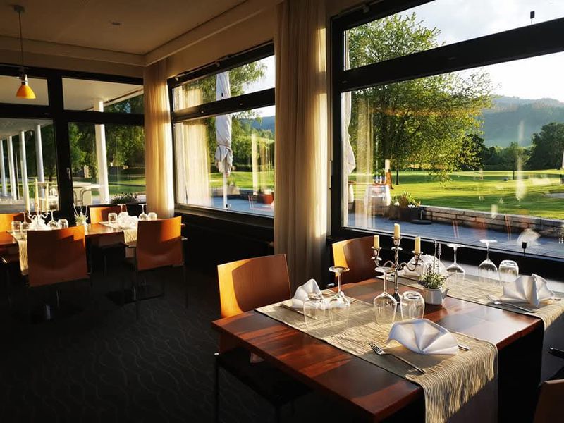 Heller Gastraum mit großen Fenstern zum Golfplatz